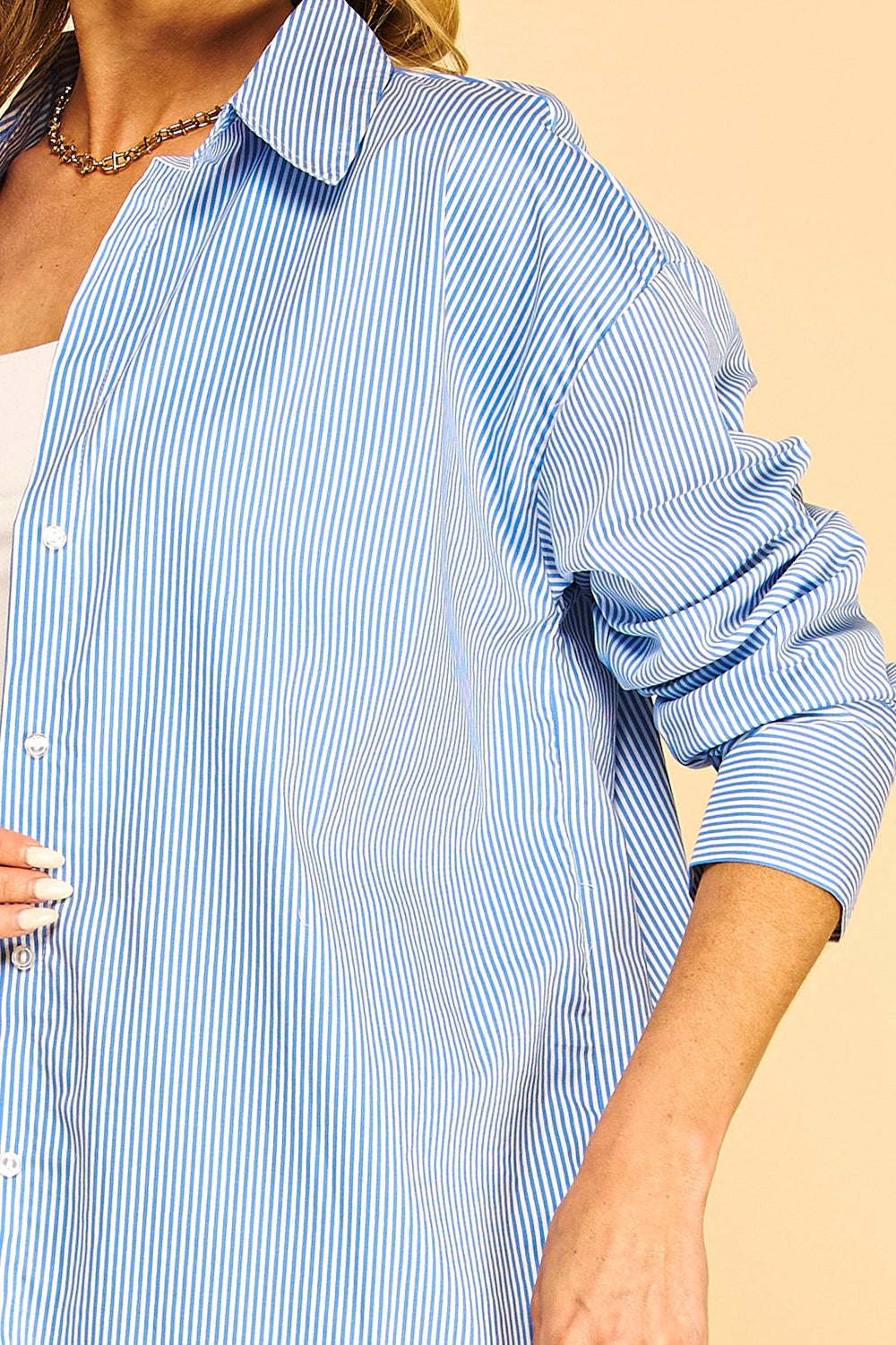 Blusa tipo camisa de manga larga con un clásico patrón de rayas verticales, cuello camisero y cierre frontal de botones.