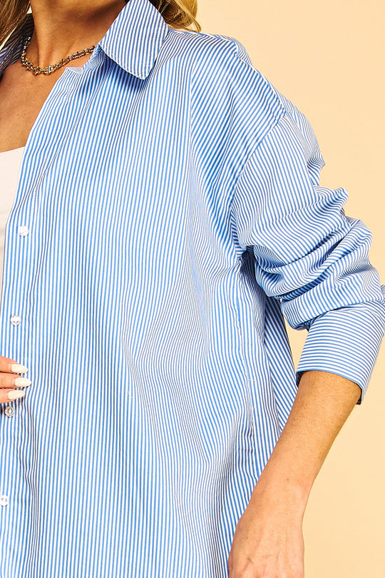 Blusa tipo camisa de manga larga con un clásico patrón de rayas verticales, cuello camisero y cierre frontal de botones.