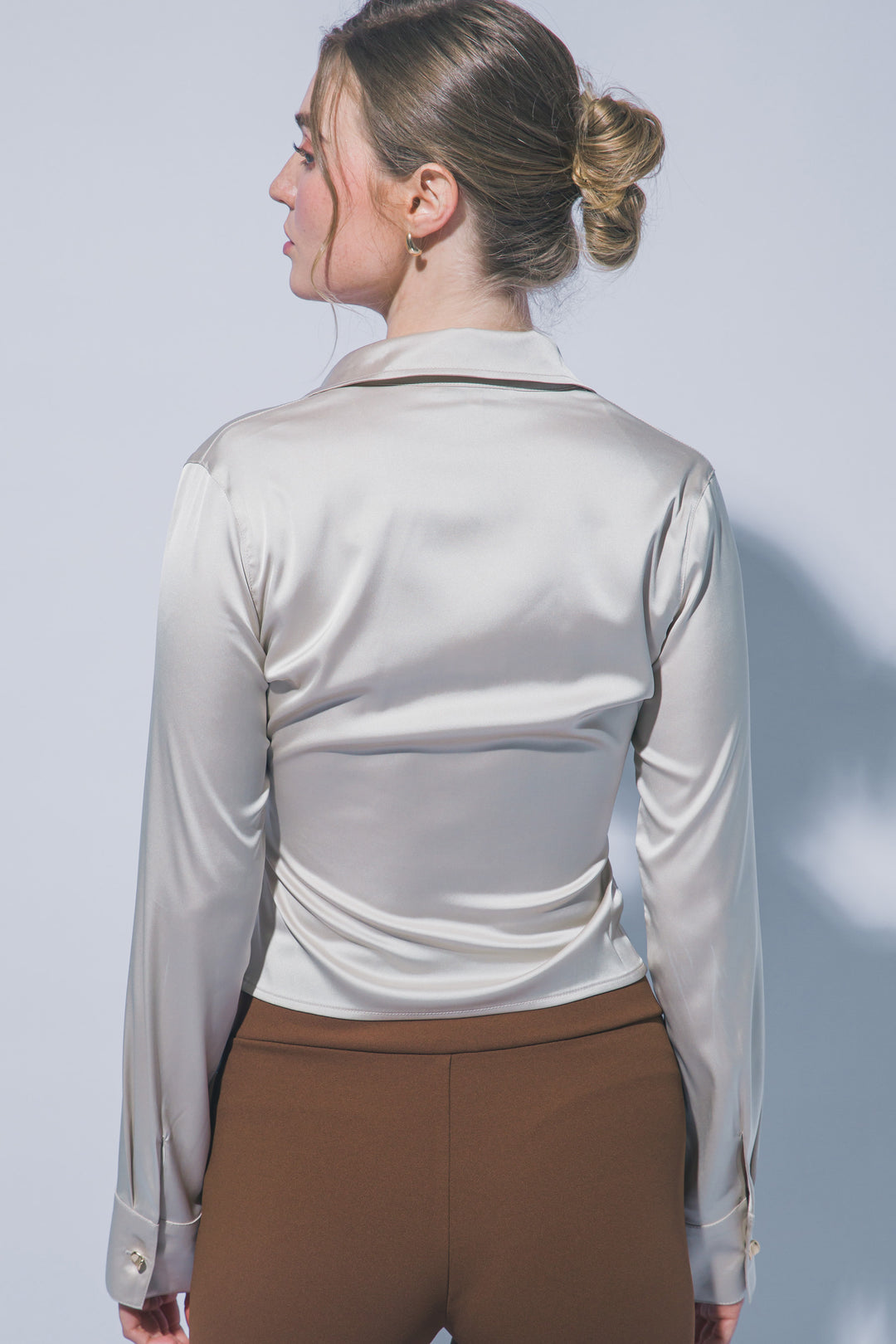 Elegante blusa de manga larga confeccionada en tejido satinado con un sutil acabado brillante
