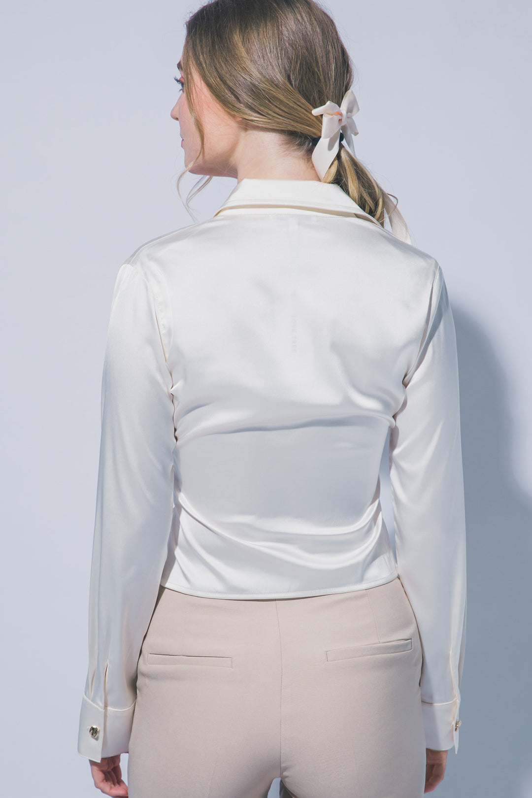 Elegante blusa de manga larga confeccionada en tejido satinado con un sutil acabado brillante
