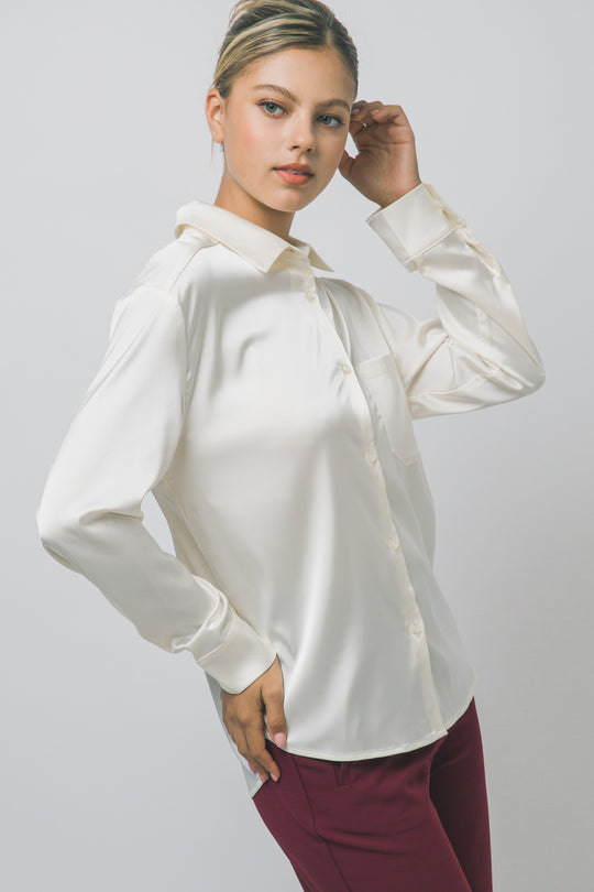 Elegante blusa de manga larga confeccionada en tejido satinado con un sutil acabado brillante en tono arena/champán