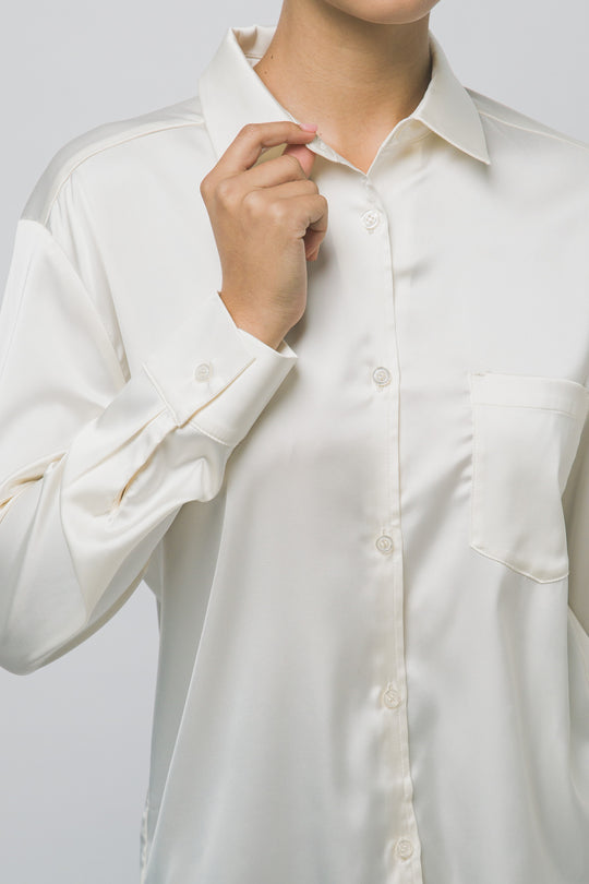 Elegante blusa de manga larga confeccionada en tejido satinado con un sutil acabado brillante en tono arena/champán