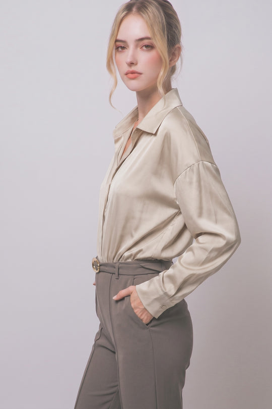 Pantiblusa estilo camisa satinada en tono perla/champán, diseñada para brindar un ajuste elegante y estilizado.