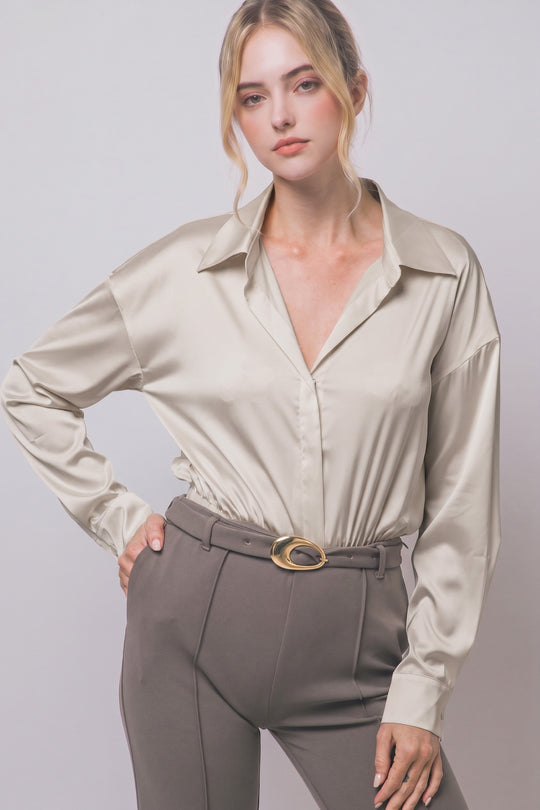 Pantiblusa estilo camisa satinada en tono perla/champán, diseñada para brindar un ajuste elegante y estilizado.