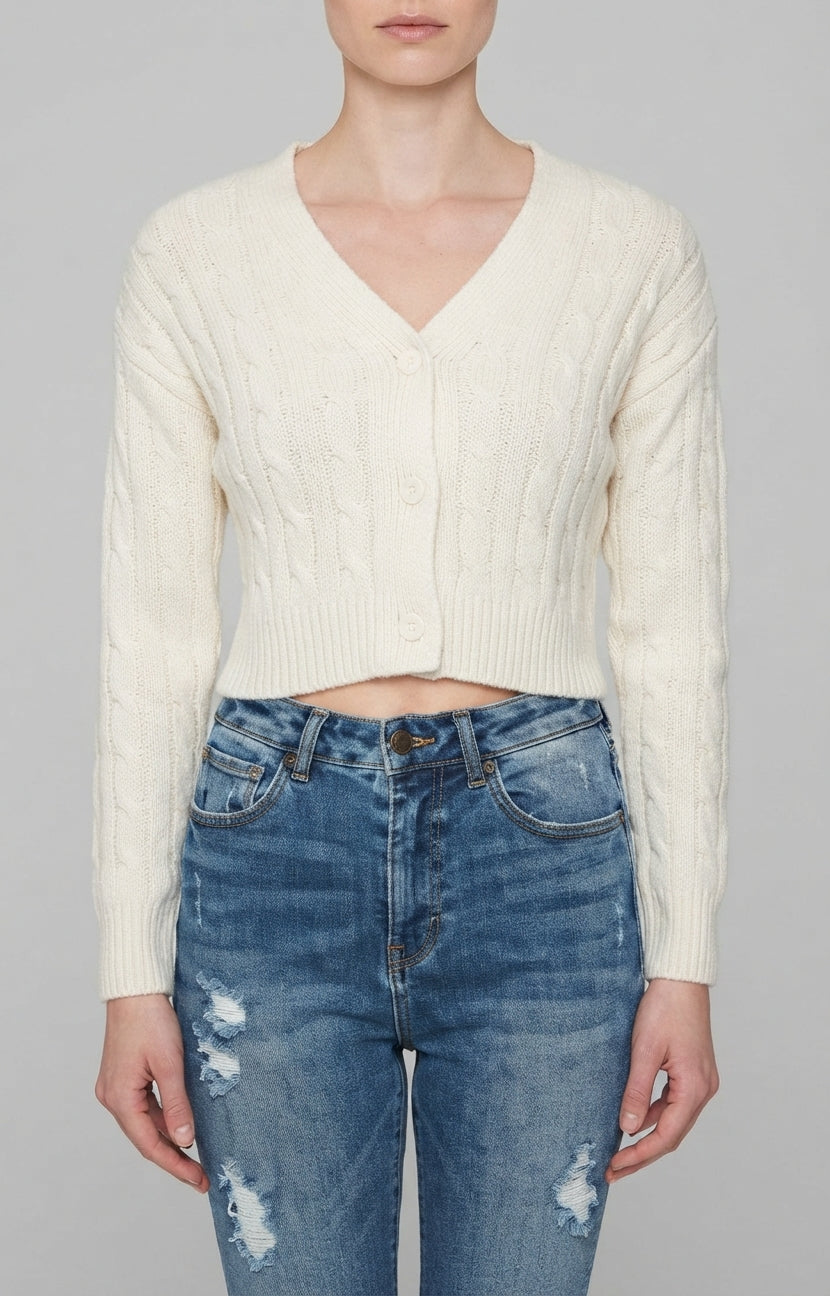 Un suéter de punto trenzado en color crema, con cuello en V y cierre frontal de tres botones