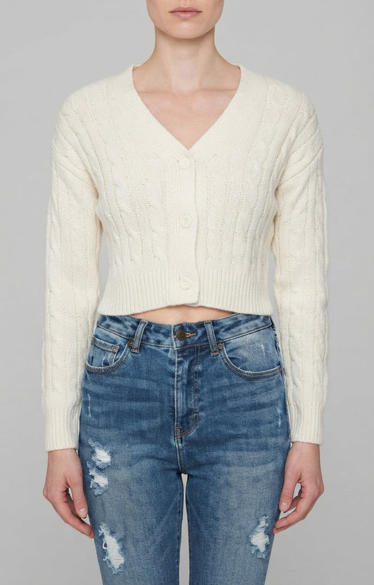 Un suéter de punto trenzado en color crema, con cuello en V y cierre frontal de tres botones